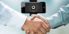 Close up of two men shaking hands in front of an iPod displaying the CitNOW sales app, iPod is mounted on a tripod