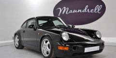 Classic Porsche car in a showroom with the Maundrell logo on the wall in the background