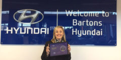 Woman holding a CitNOW awards winner certificate in front of the dealership sign
