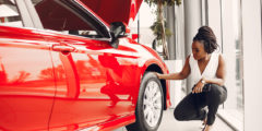 Woman looking at the tyre of a red car in the showroom