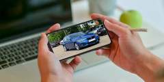 Close up image of a person looking at their phone which has a fullscreen photo of a new blue BMW car on it.