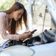 A woman taking a video of an issue she is having under the bonnet of her car.